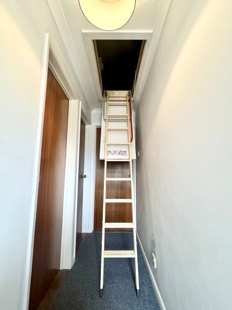 A white folding loft ladder fitted by CB Lofts, extended down to a carpeted landing